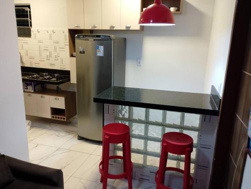ベレンにあるApartamento novo e confortávelのキッチン(カウンターと赤いスツール2脚付)