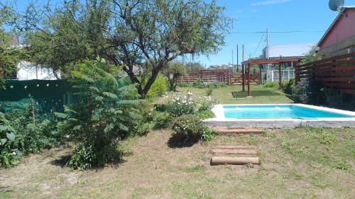 einen Hinterhof mit einem Pool und einem Baum in der Unterkunft Cabaña Carlos Paz in Villa San Nicolás