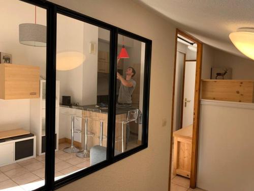 a man standing in front of a mirror in a kitchen at Appartement vue piste de ski in Praz-sur-Arly