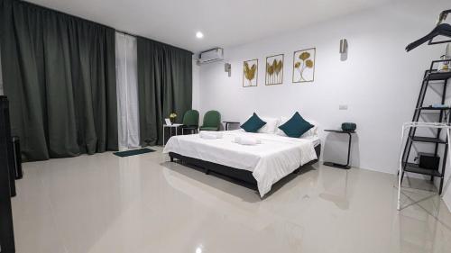 a bedroom with a white bed and green curtains at Chu-Cha's Rooms in Koh Samui 