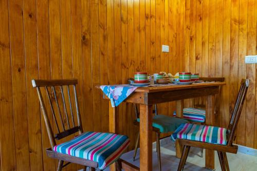 a wooden table with two chairs and a table with cups at Mi Sueño Bed and Breakfast in Aluminé