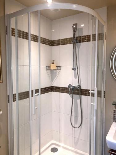 une douche avec une porte vitrée dans une salle de bain dans l'établissement Reglisse et Pain d'Epices - Chambres d'hôtes, à Honfleur