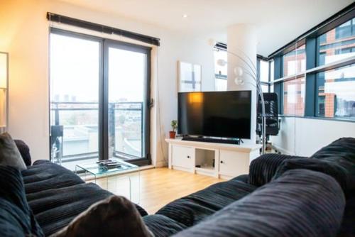 a living room with a couch and a flat screen tv at Modern 2-Bed Flat with Breathtaking City Views in Leeds