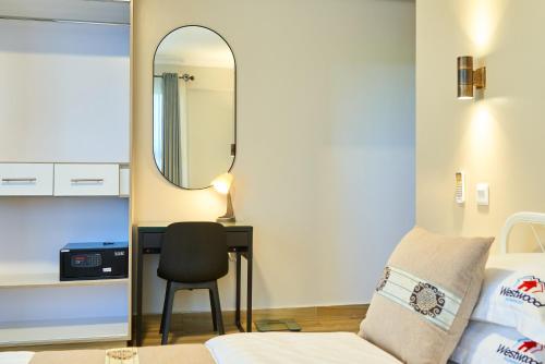 a bedroom with a bed and a desk with a mirror at Westwood Residences in Arusha
