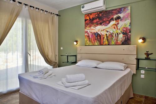 a bedroom with a bed with a painting on the wall at Axion Esti Apartments in Skopelos Town