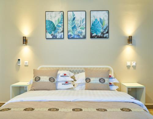 a bedroom with a bed with four pictures on the wall at Westwood Residences in Arusha