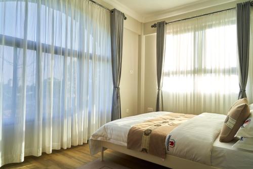 a bedroom with a bed and a large window at Westwood Residences in Arusha