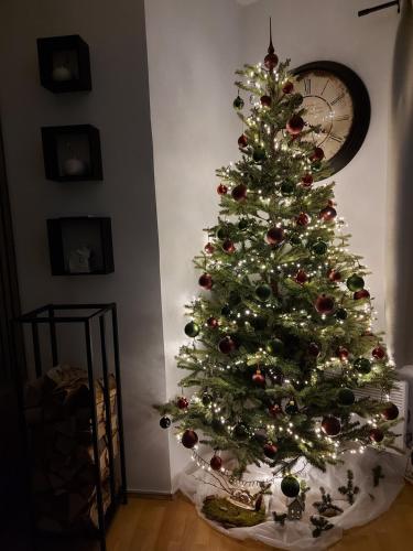 Un árbol de Navidad en una habitación con reloj en Apartment - Golden Fox 18 - Pohorske terase, en Hočko Pohorje