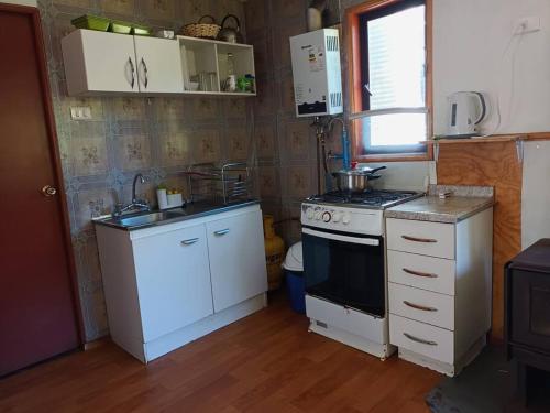 uma pequena cozinha com um fogão e um lavatório em Cabaña a metros de la playa San Ignacio, Niebla em Valdivia