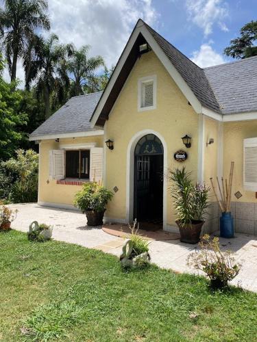 uma casa amarela com uma porta preta num quintal em La Foresta em Rincón del Pino