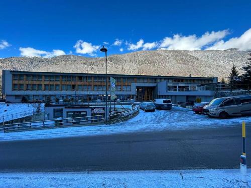 a building with cars parked in a snow covered parking lot at La Baipa Accesso piste in Mezzana