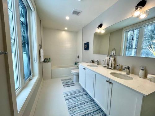 a bathroom with two sinks and a toilet and a mirror at Cozy Muskoka 4-bedroom cottage on Lake Rosseau in Minett