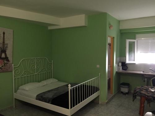 een groene slaapkamer met een bed en een wastafel bij Tenerife Hostel in Los Cristianos