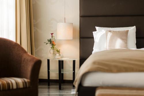 a bedroom with a bed and a table with a vase of flowers at Hotel Timisoara in Timişoara