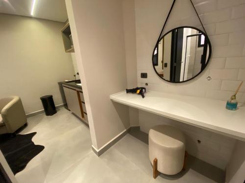 a bathroom with a mirror on a counter and a stool at Villa Cristalle - Campos do Jordão in Campos do Jordão