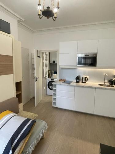 a kitchen with white cabinets and a bed in a room at Appartement Vincennes cozy in Vincennes