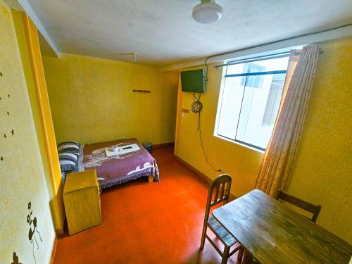 una camera con un letto, un tavolo e una finestra di HOSTAL DALIA a Chivay