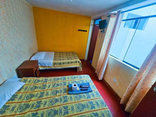 a hotel room with two beds and a large window at HOSTAL DALIA in Chivay