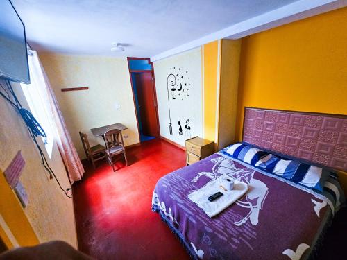 Un dormitorio con una cama y una mesa. en HOSTAL DALIA, en Chivay