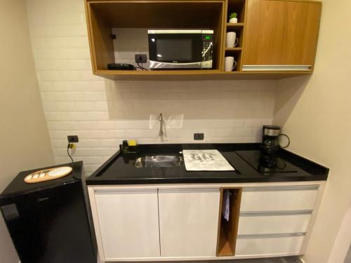 a small kitchen with a sink and a microwave at Villa Cristalle - Campos do Jordão in Campos do Jordão