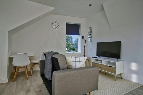 ein Wohnzimmer mit einem Sofa und einem TV in der Unterkunft GuestReady - Comfortable Leeds City Apartment in Kirkstall