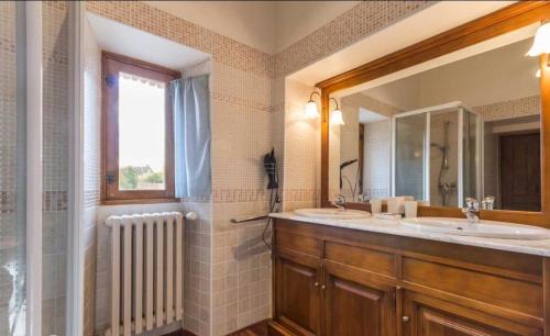 にあるManoir du Petit Logisのバスルーム(洗面台2台、鏡、窓付)