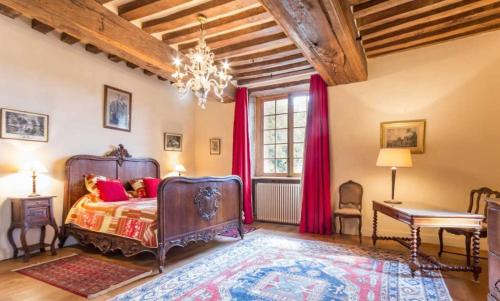 a bedroom with a bed and a chandelier at Manoir du Petit Logis 