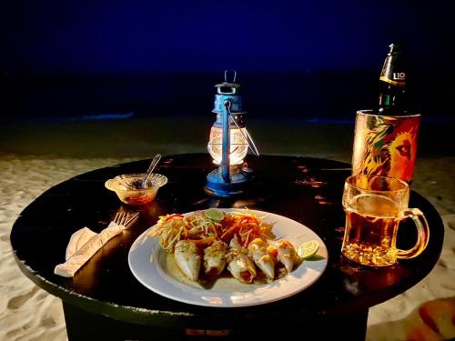 una mesa con un plato de comida y un vaso de cerveza en Sasagara Beach Villa, en Tangalle