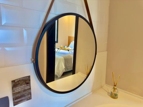a round mirror on a wall in a bathroom at Villa Cristalle - Campos do Jordão in Campos do Jordão