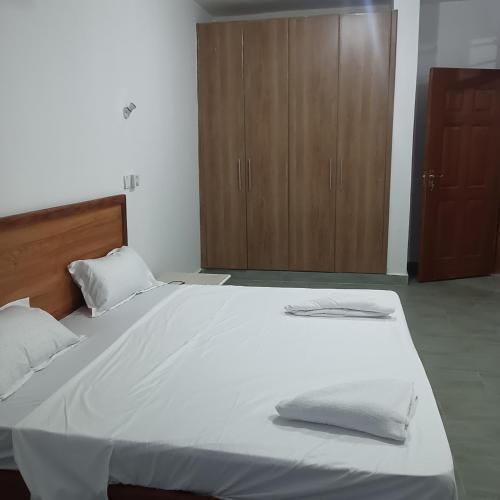a large white bed with two pillows and a wooden cabinet at Jade luxury apartments Diani in Mombasa