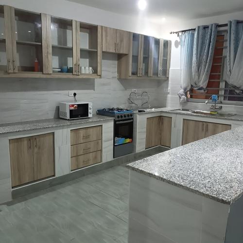 a kitchen with wooden cabinets and a stove top oven at Jade luxury apartments Diani in Mombasa