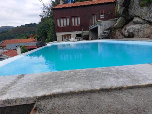 une grande piscine bleue en face d'une maison dans l'établissement Casa Pinhão de Sousa, à Vieira do Minho