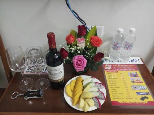 stół z butelką wina oraz talerzem owoców i kwiatów w obiekcie Motel Hằng Hiên 