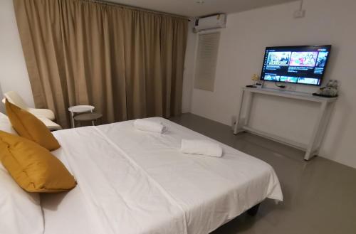 a bedroom with a white bed and a television at Chu-Cha's Rooms in Koh Samui