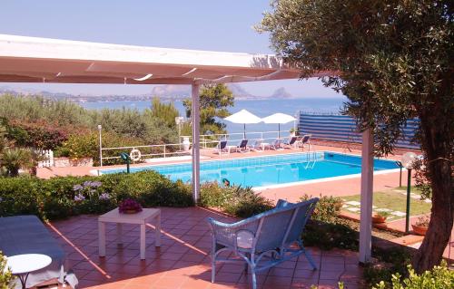 a swimming pool with a table and chairs and an umbrella at Casetta Nikà in Altavilla Milicia