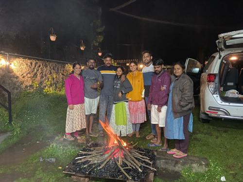 a group of people standing around a fire at Sun cool stay cottage in Kodaikānāl