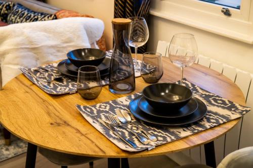 a wooden table with plates and wine glasses on it at Kirkgate Suites - Stylish City Centre Apartment in Leeds