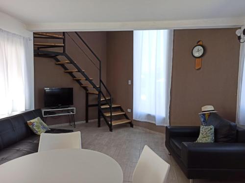 ein Wohnzimmer mit einem schwarzen Sofa und einer Treppe in der Unterkunft Casa vacacional LUNA DE MAR in Santa Clara del Mar