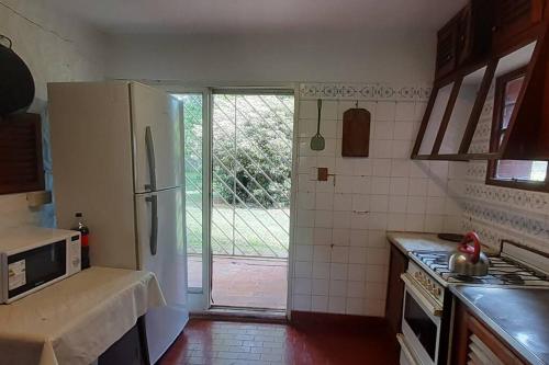 a kitchen with a refrigerator and a door to a yard at Lima - Casa rural - Pileta - 11 camas in Lima