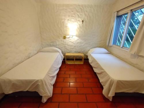 two beds in a small room with a window at Lima - Casa rural - Pileta - 11 camas in Lima