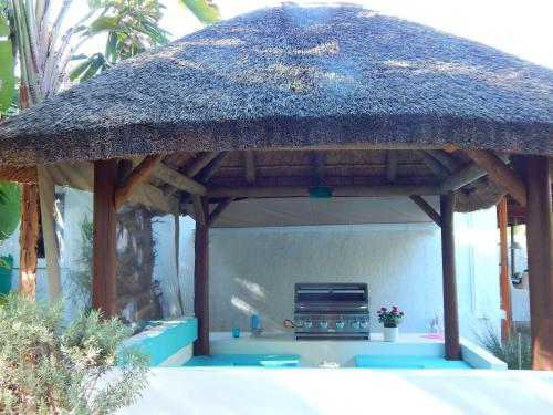 a straw roofed gazebo with a grill at Khashamongo B & B in Somerset West