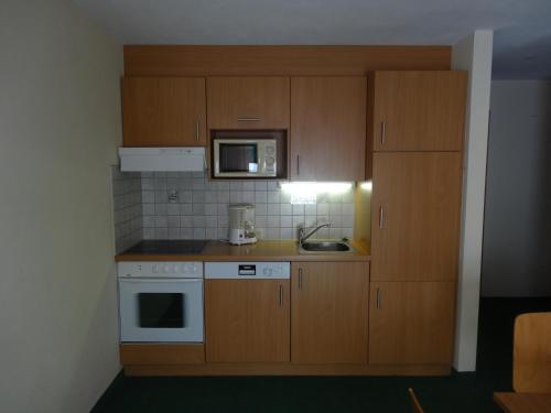 a small kitchen with wooden cabinets and a microwave at Köflerhof Appartements in Sankt Leonhard im Pitztal