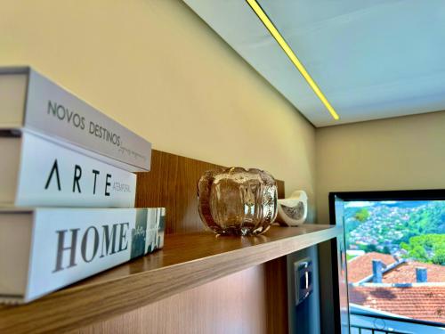 a shelf in a room with a tv and a vase at Villa Cristalle - Campos do Jordão in Campos do Jordão