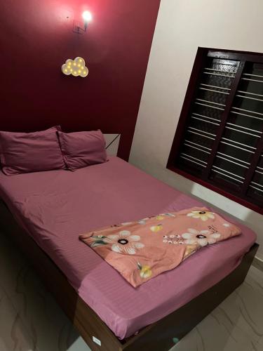 a bed with a pink comforter with flowers on it at Dragster Homes in Kizhake Chālakudi