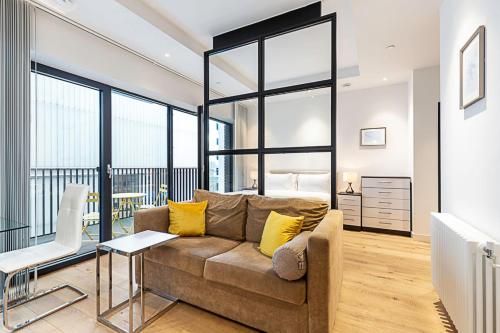 a living room with a couch and some windows at Chic Studio Living in London City Island in London
