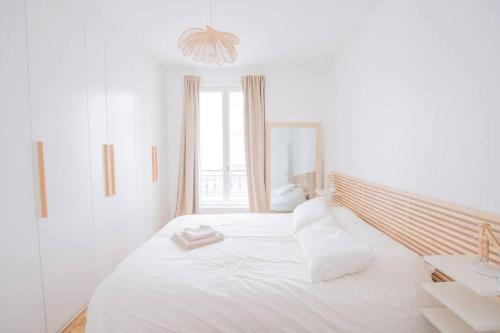 une chambre blanche avec un grand lit avec des oreillers blancs dans l'établissement We Parisian The Latin Quarter Cozy Home, à Paris