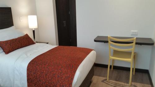 a bedroom with a bed and a desk and a chair at AZ Hotel in Bogotá
