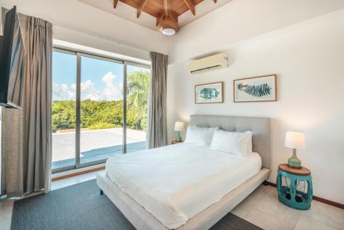 - une chambre avec un lit et une grande fenêtre dans l'établissement Luxurious and modern Villa with Pool at Yarari, à Punta Cana