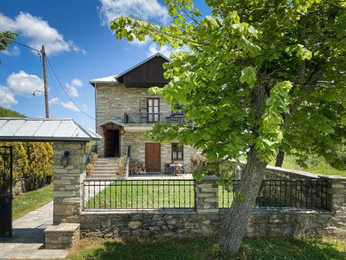 una casa de piedra con una valla y un árbol en Villa Arcturia, en Nymfaio