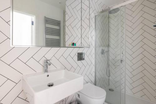 a white bathroom with a sink and a toilet at Gorgeous, Modern apartment-fantastic location in Slough